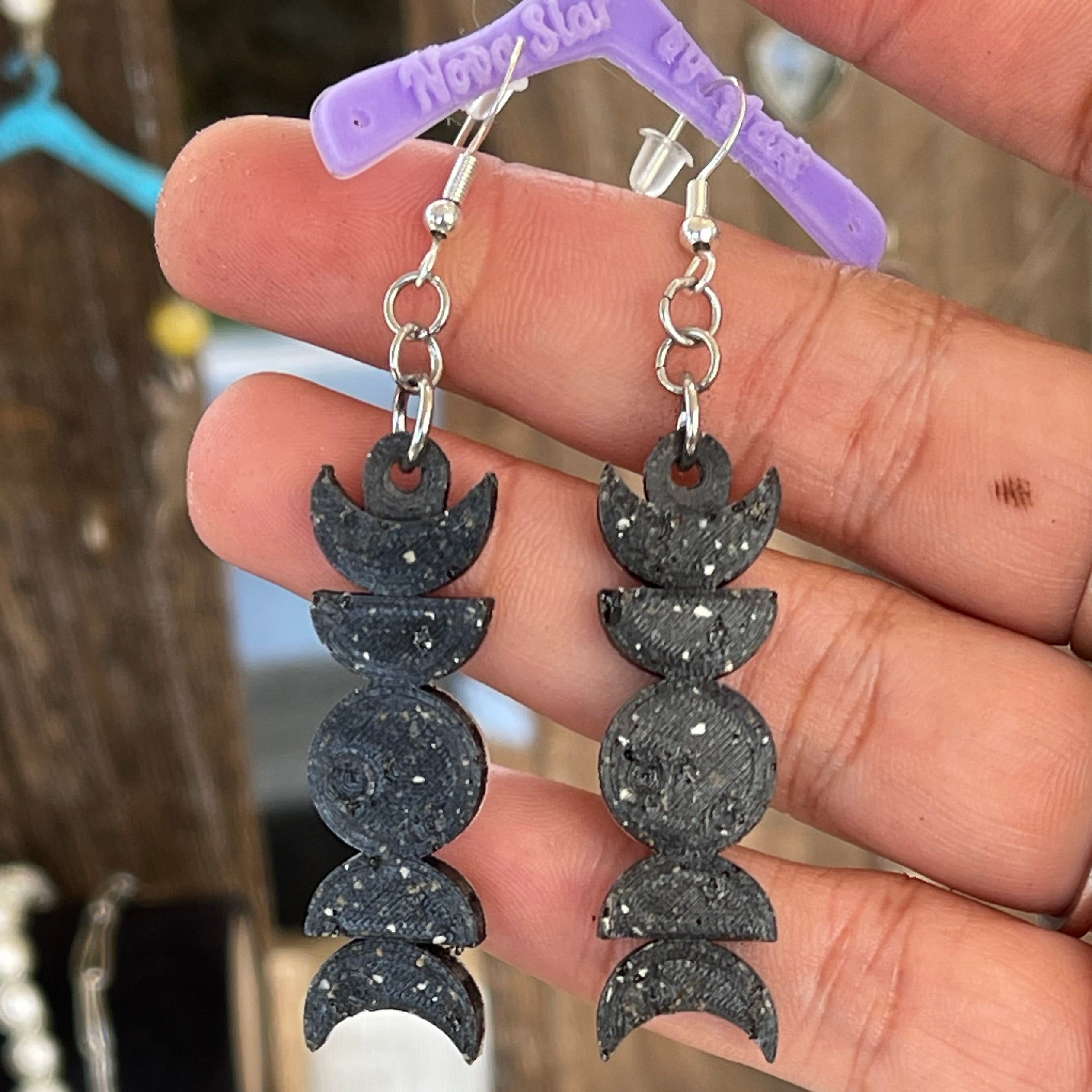 Bracelet with moon phase design held by a hand against a blurred background